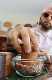 Hand dipping a Dirty Cookie cookie shot into a bowl of rainbow sprinkles