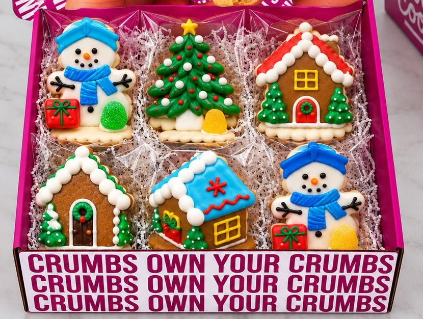 Six decorated winter cookies: two snowmen, a frosted tree and three mini gingerbread houses