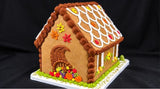 Side of the harvest gingerbread house with a cornucopia spilling with pumpkins and fall leaves under a scalloped roof