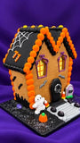 Haunted Halloween gingerbread house with a spiderweb roof, ghosts in the windows, a mummy on the porch and a coffin front door